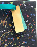 UK Greetings medium gift bag with party design, suitable for him, her, or friends, featuring colorful decorative elements.