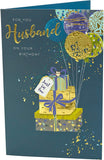 UK Greetings contemporary husband birthday card with colorful balloons attached to wrapped gift, celebrating special occasions.