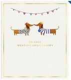 UK Greetings anniversary greeting card featuring playful sausage dogs and bunting, with a subtle watermark design.