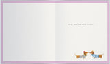 UK Greetings anniversary greeting card featuring playful sausage dogs and bunting, with a subtle watermark design.