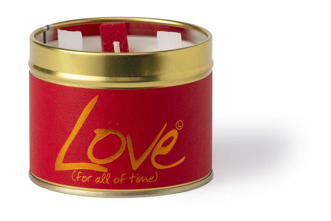 Lily-Flame Love scented tin candle with a decorative label, small round metal container with a lit candle inside.