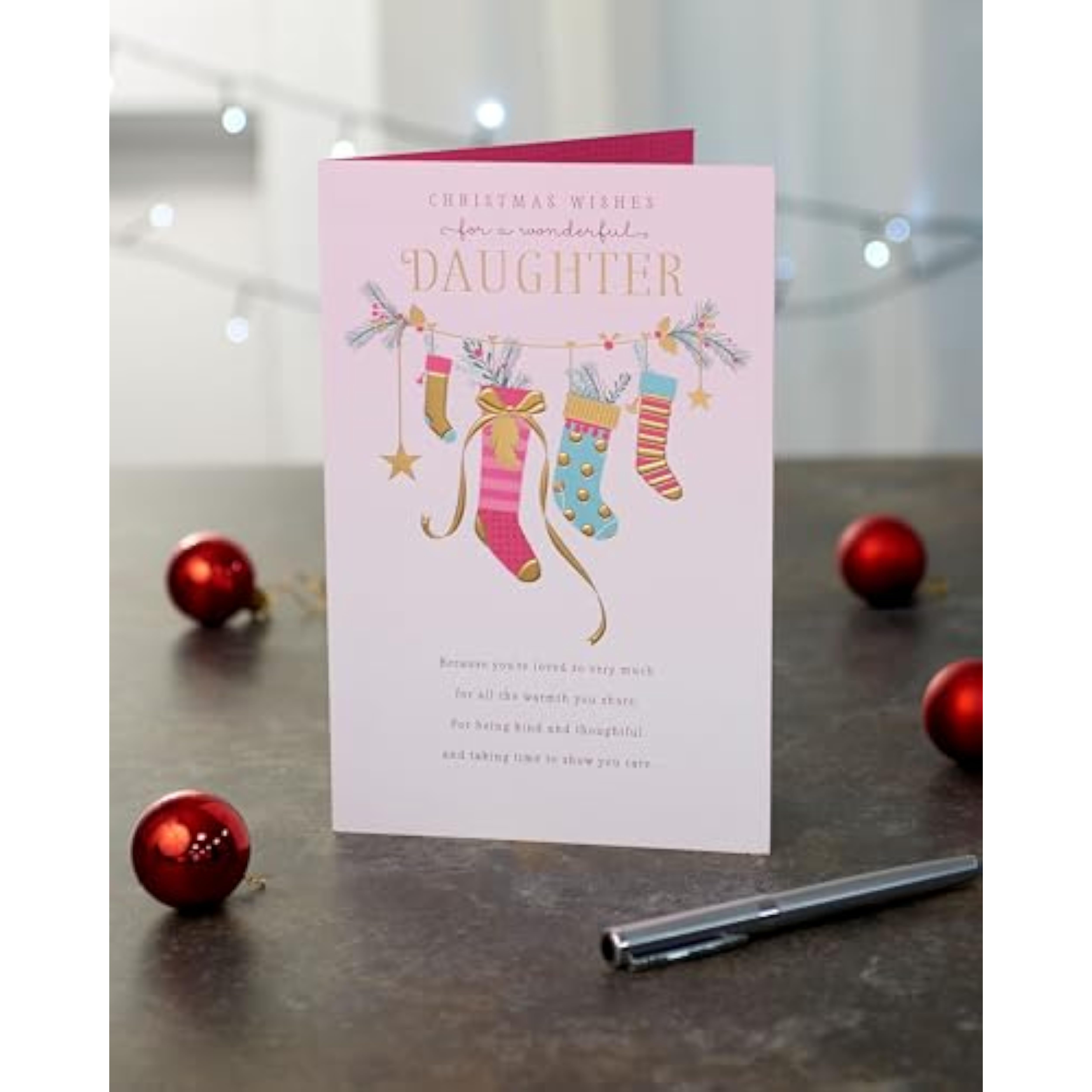 UK Greetings Christmas card for daughter featuring pink stockings design, festive holiday greeting with cheerful holiday imagery.
