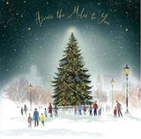 UK Greetings Christmas card featuring a village with a snow-covered Christmas tree and festive holiday scene.