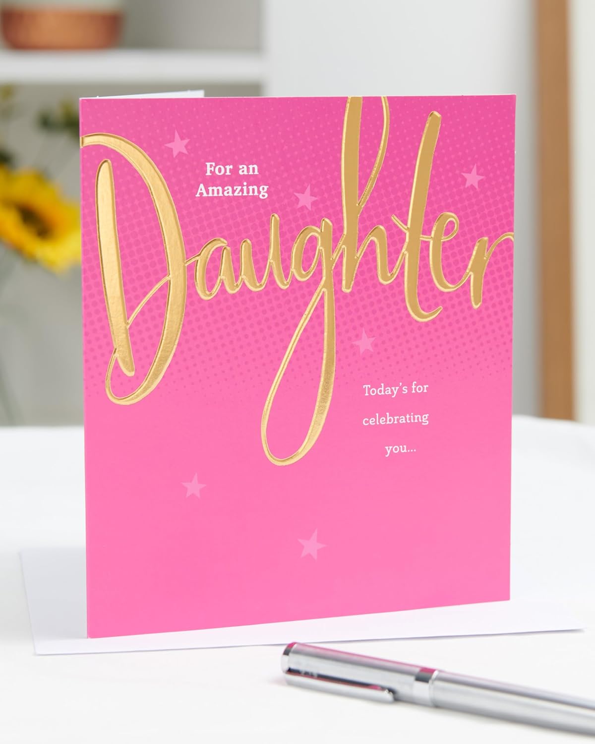 Pink and gold UK Greetings birthday card for daughter with floral design and celebratory message, featuring elegant decorative elements.