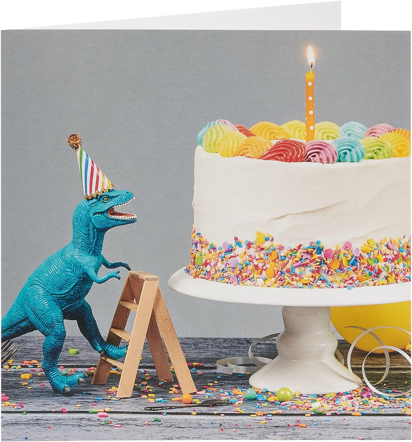 UK Greetings birthday card for him or friend featuring colorful cake and dinosaur design, perfect for celebrating birthdays.