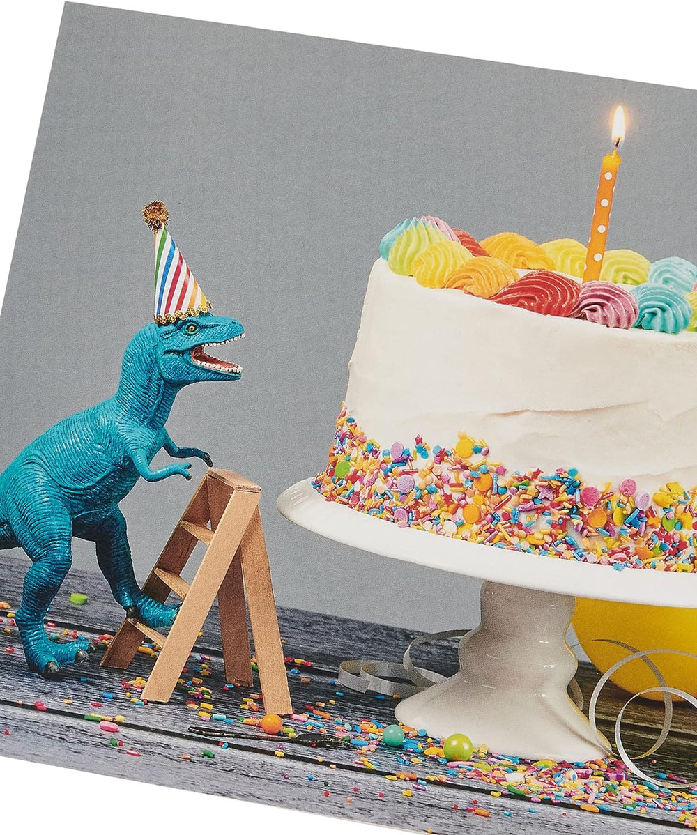 UK Greetings birthday card for him or friend featuring a colorful cake and dinosaur design, perfect for celebrating special occasions.