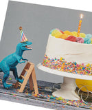 UK Greetings birthday card for him or friend featuring a colorful cake and dinosaur design, perfect for celebrating special occasions.