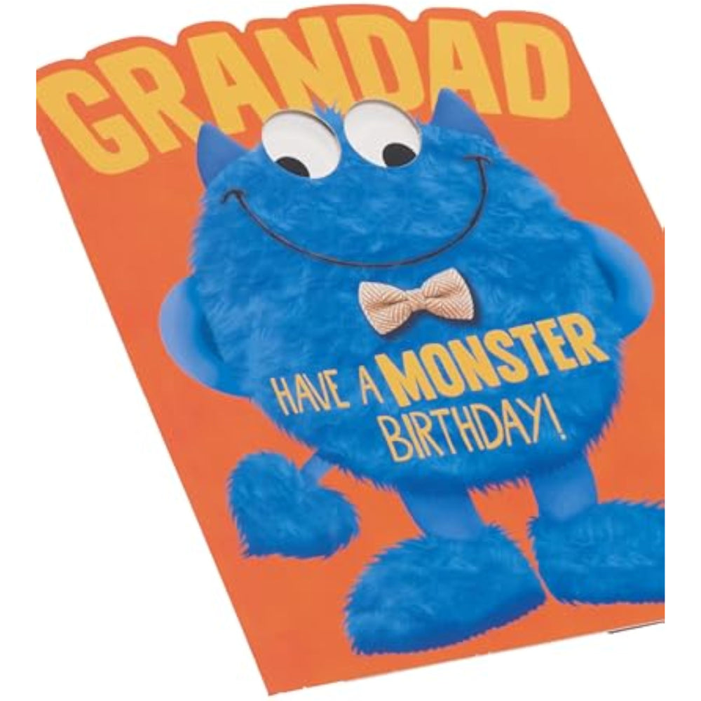 Blue googly-eyed monster Grandad birthday card by UK Greetings, featuring a cheerful cartoon monster with colorful decorations.