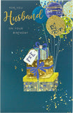 UK Greetings contemporary husband birthday card with colorful balloons attached to wrapped gifts, perfect for celebrating his special day.
