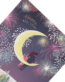 UK Greetings Christmas and New Year greeting card featuring a couple sitting on a half moon illustration.