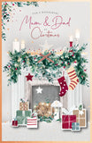 UK Greetings Christmas greeting card featuring a cozy fireplace scene with "Mum and Dad" messages for holiday wishes.