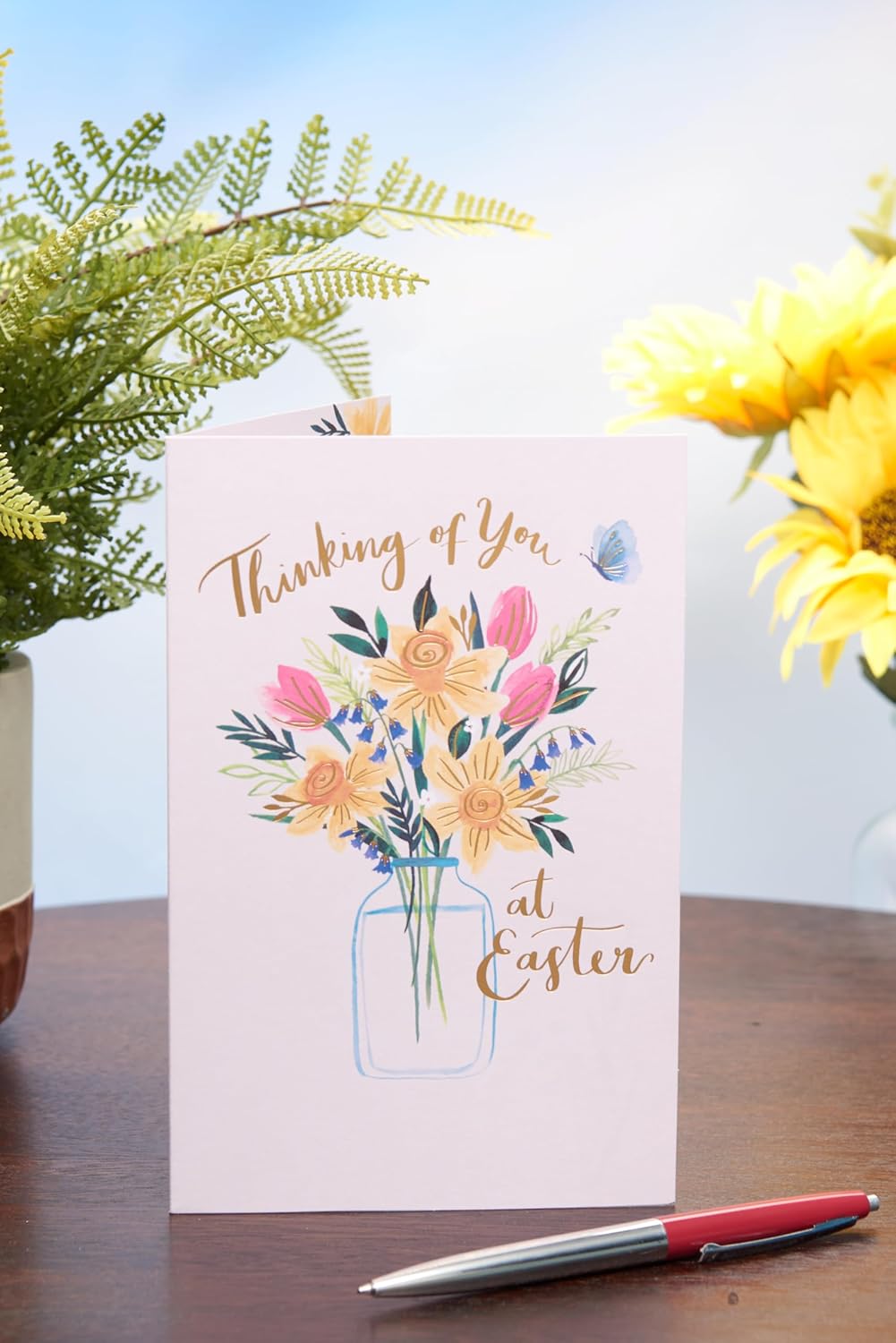 UK Greetings Easter card featuring daffodils in a vase with the message "Thinking of You" on floral stationery design.